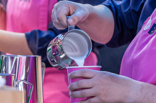 Aufgeschäumte Milch wird in ein Becher gegossen.