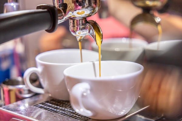 Es läuft Espresso aus der Maschine in 2 Tassen